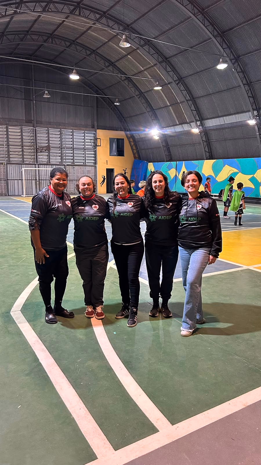 Equipe de professoras do Futsal na Escola reunida na quadra, de uniforme do projeto.