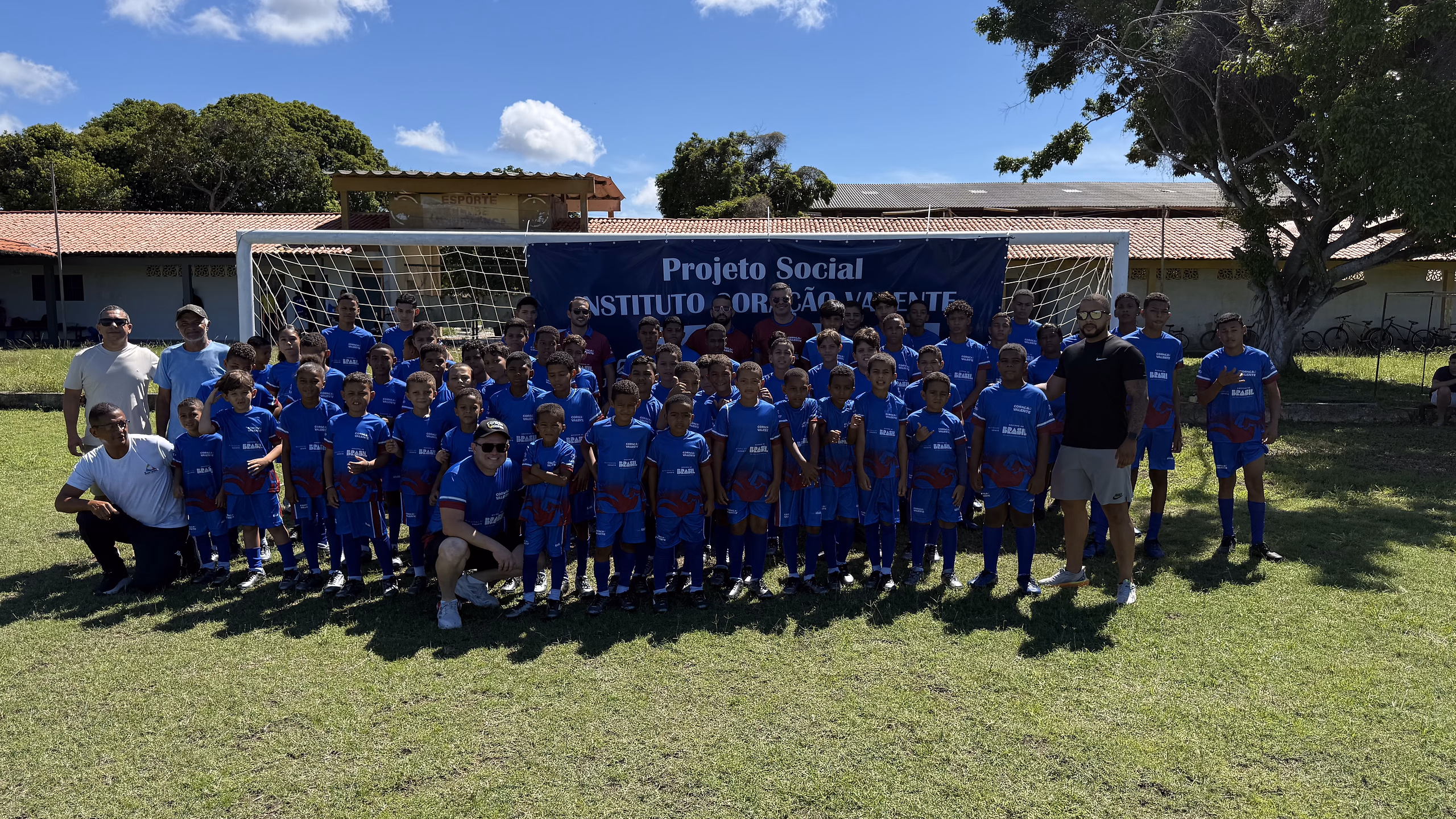 Turma do Coração Valente reunida no campo do polo de Estância, diante do painel do projeto.